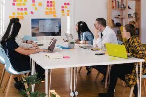 several people in a business setting looking at brightly colored post-it notes on a wall